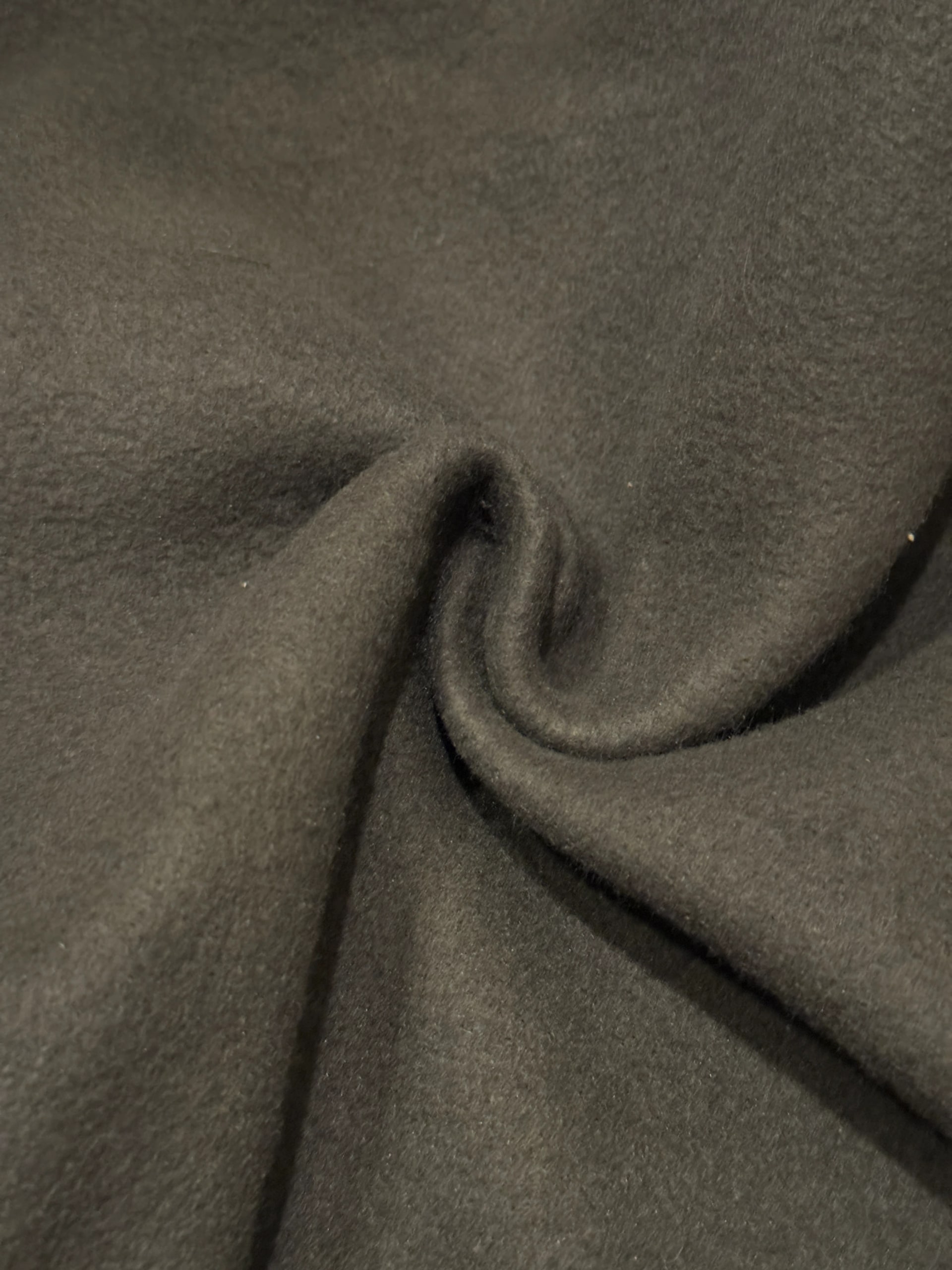 Close-up of dark olive heavyweight cotton, folded into a soft swirl.